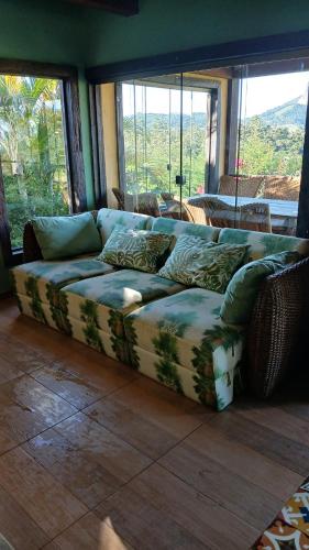 a couch sitting in a living room with windows at Casa Vista da Pedra - 10km de Pedra Azul in Domingos Martins