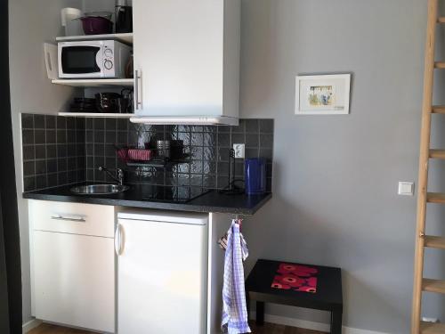 a kitchen with white cabinets and a sink at Ljungs Fem Rum in Västergarn