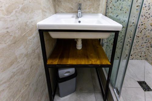 a bathroom sink with a wooden shelf under it at 1 room apartment CITY PLUS 1 in Almaty