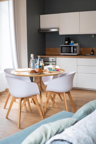 une cuisine avec une table et deux chaises blanches dans l'établissement Studio Vichy patrimoine mondial Villa Marie Celine, à Vichy