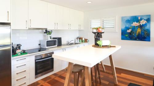 a kitchen with white cabinets and a white table at Perfect weekend getaway plus golf at your doorstep in Salamander Bay