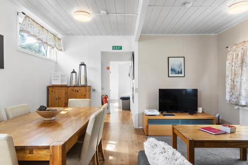 a dining room with a table and a television at Cozy house by the river Ytri Rangá in Hella