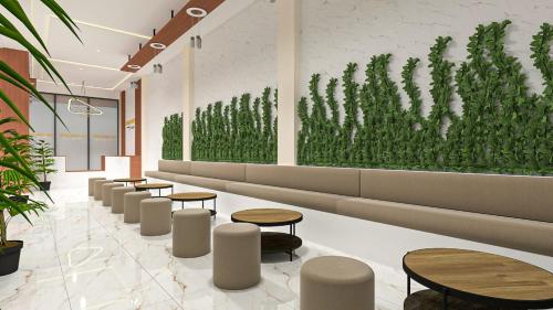 a lobby with tables and chairs and a green wall at Garuda Hotel By Calandra in Banda Aceh