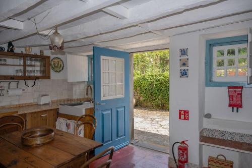 a kitchen with a blue door and a table in it at New Family Country House in Colares