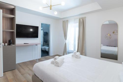 a white bedroom with a large bed and a tv at Maison Rasella Palace Suites in Rome
