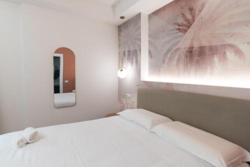 a white bedroom with a bed and a mirror at Maison Rasella Palace Suites in Rome