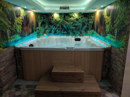 a jacuzzi tub with a jungle themed wall at Family Hotel Teos in Kiten