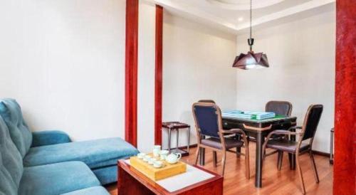 a living room with a couch and a table and chairs at GreenTree Inn Kunming Baiyun Road Tongde Plaza Branch in Kunming