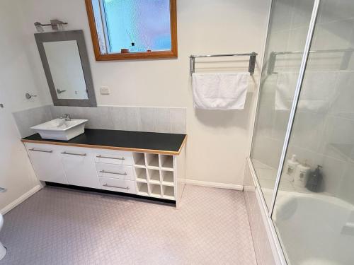 une salle de bain blanche avec lavabo et douche dans l'établissement Central Sandy Bay Retreat, à Sandy Bay