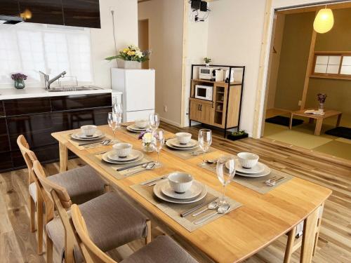 - une table en bois avec des assiettes et des verres dans la cuisine dans l'établissement Lampstand STAY Sapporo B栋 独立整层 3房2卫 可住6人 免费停车 近地铁与商圈, à Sapporo
