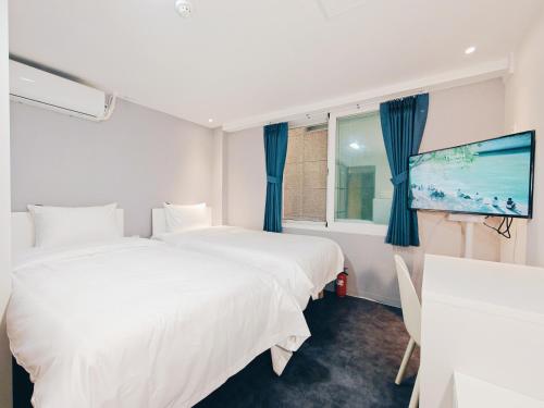 ソウルにあるW hostelのベッド2台とテレビがあるホテルの部屋