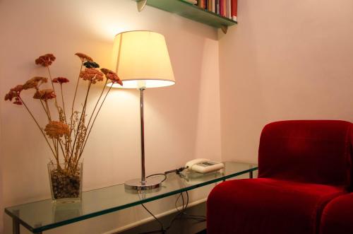 a room with a glass table and a lamp and a red chair at Hotel Garda in Rome