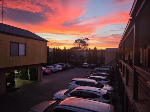 a row of cars parked in a parking lot at sunset at Seaview Motel & Apartments in Apollo Bay
