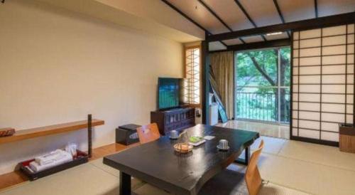 a living room with a table and chairs and a window at Hotel Myoken Tanaka Kaikan in Kirishima
