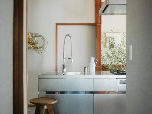 a kitchen with a sink and a counter with a stool at マイグレフラット in Ito