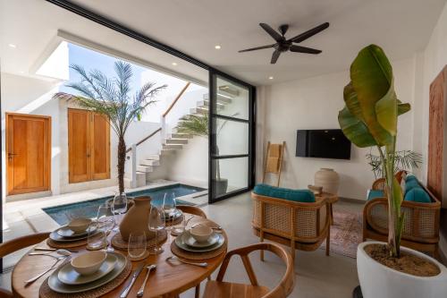 a dining room with a table and a living room at Enaya Villa by Betterplace in Tumbak Bayuh