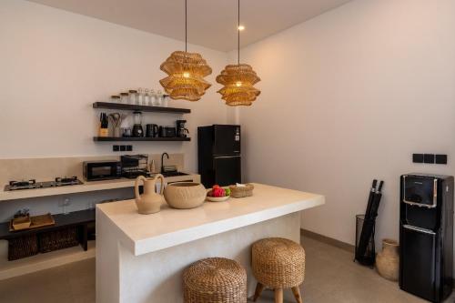a kitchen with a counter with two chairs and a refrigerator at Enaya Villa by Betterplace in Tumbak Bayuh