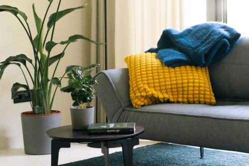 a living room with a couch with a yellow pillow and a table at RELAX HILL Vendégház in Dunabogdány