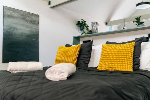 a bedroom with a black bed with yellow pillows at RELAX HILL Vendégház in Dunabogdány