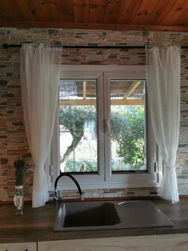 a kitchen window with white curtains over a sink at Kefalonia Olive House private pool in Xi