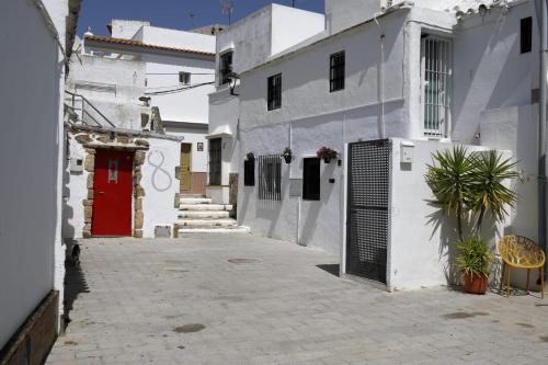 an alley with white buildings and a red door at La casita de Paco in Barbate