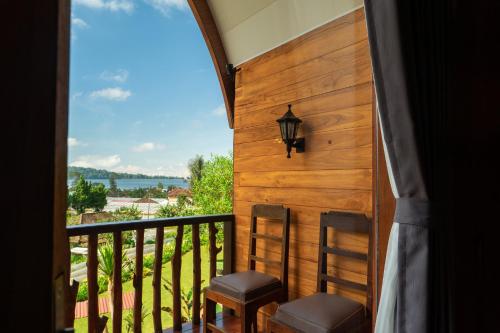 a balcony with two chairs and a view of the water at Pondanu Living in Bedugul