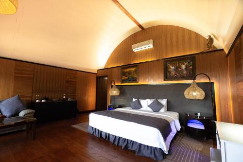 a bedroom with a large bed and a couch at Pondanu Living in Bedugul