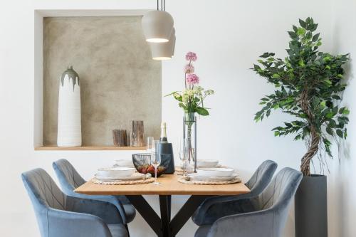 a dining room table with blue chairs and a table with flowers at FENJOY Ferienapartments Bernau am Chiemsee in Bernau am Chiemsee