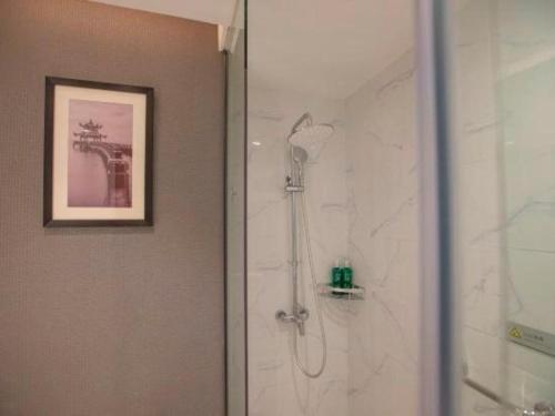 a shower in a bathroom with a picture on the wall at Magnotel Hotel Dongxing Guomen Port in Fangcheng