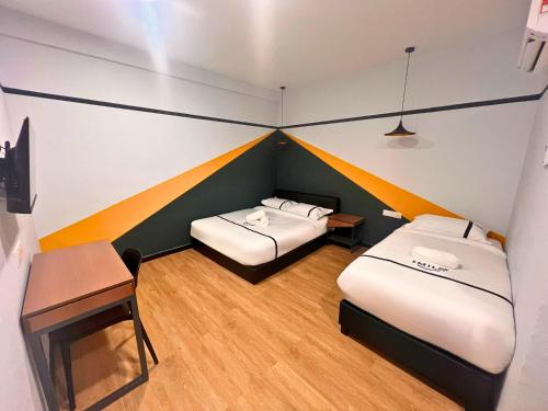 八打灵再也Seeds Hotel Damansara Pelangi的客房设有两张床、一张桌子和一张书桌。