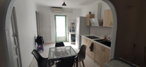 une petite cuisine avec une table et des chaises en verre dans l'établissement Maison T3 clim bus C3 proche centre terrasse, à Avignon