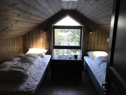 Una pequeña habitación con dos camas y una ventana. en High standard Cabin close to Norefjell, 