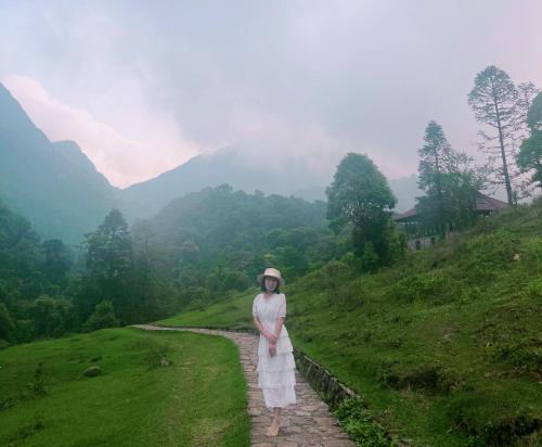 a woman in a white dress standing on a path at Bamboo Home in Sa Pa