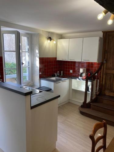 une cuisine avec des armoires blanches et un comptoir noir dans l'établissement City center Old port La Rochelle, à La Rochelle