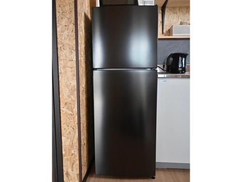 a black refrigerator in a kitchen next to a counter at ｹﾞｽﾄﾊｳｽ ﾊﾞｲｸﾔﾉﾆｶｲ in Hagi