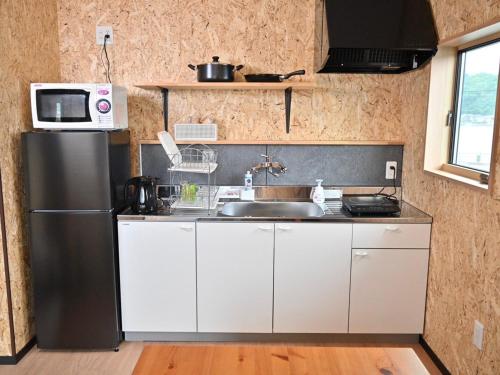 a kitchen with a stainless steel refrigerator and a sink at ｹﾞｽﾄﾊｳｽ ﾊﾞｲｸﾔﾉﾆｶｲ in Hagi