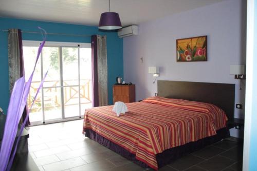 a bedroom with a bed and a large window at Hotel L'ebene Verte in Matoury