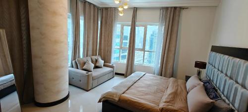 a bedroom with a bed and a couch and a large window at JLT 1BR Marina Skyline View in Dubai