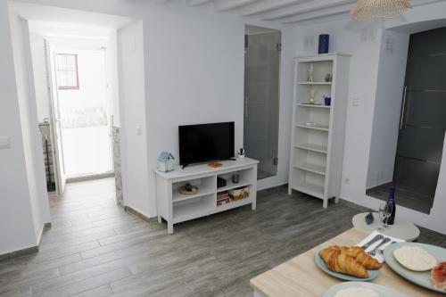 a white living room with a tv and a table at La casita de Paco in Barbate
