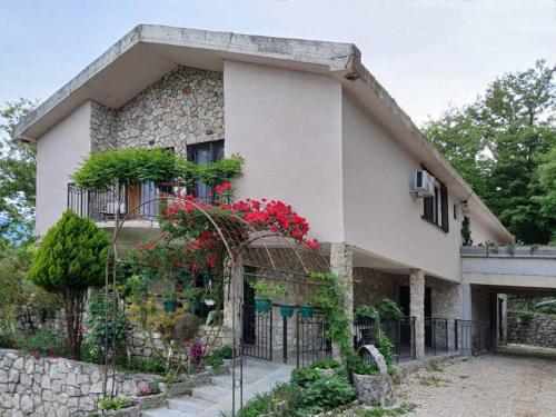 a house with red flowers on the side of it at Dado in Virpazar