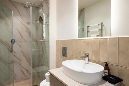 une salle de bain avec un lavabo et une douche dans l'établissement Luxury at The Braemar, Green Point, au Cap