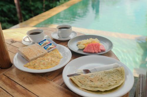 een tafel met borden en twee kopjes koffie bij Adipana Bungalow-Balinese Room in Ubud