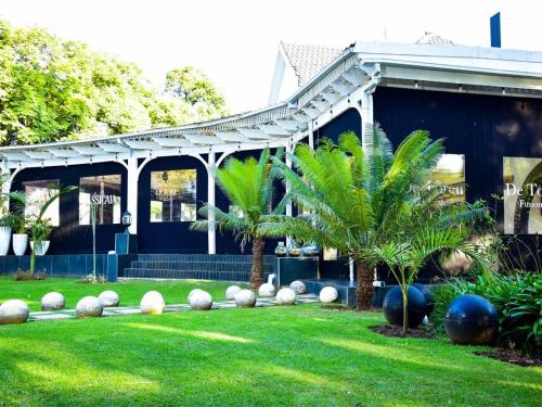 a house with two palm trees in the yard at C'est La Vie Boutique Hotel in Witbank