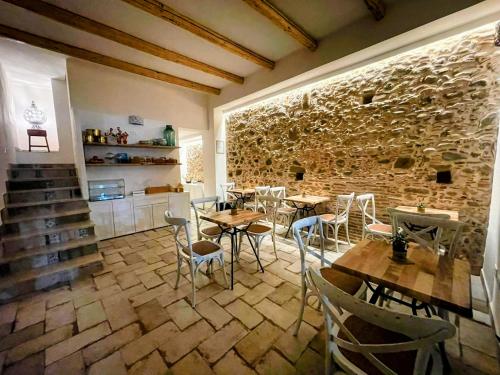 a restaurant with tables and chairs and a stone wall at Scirocco Affittacamere in Oliveri