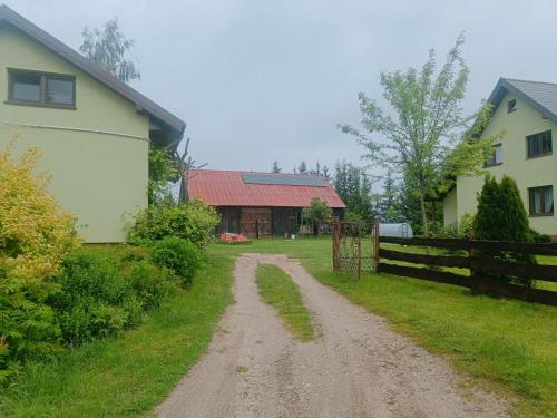 a dirt road next to a house and a fence at Domek Pszczelarza in Krasnopol