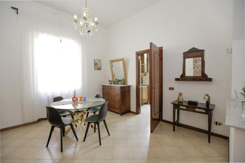 a dining room with a table and chairs and a chandelier at Spazioso appartamento con Giardino a Parcheggio Gratuito in Massa