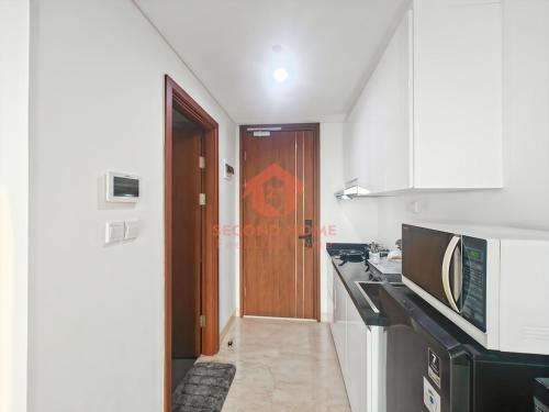 a kitchen with a sink and a microwave at Cozy Studio South Gate Apt with Pool, Gym, Wi-Fi by 2ndHome in Jakarta