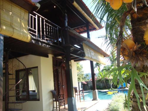 a house with a balcony next to a pool at Atres Villa in Munduk