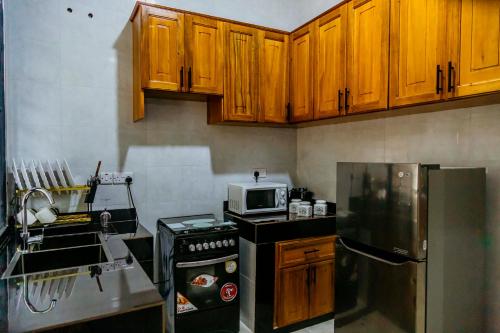 a kitchen with wooden cabinets and a stove and a microwave at Dodo homes in Uru
