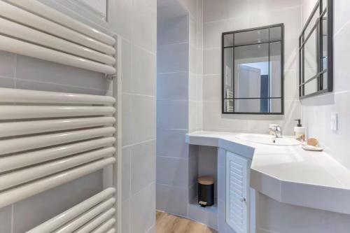 une salle de bain blanche avec un lavabo et un miroir dans l'établissement L'Anglais,Charmant T2,Pour 4 adultes et 1 enfants, à Pau